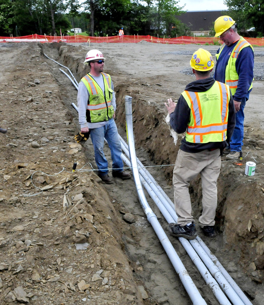 Subcontractors lay conduit to carry electricity from the new solar array under construction near Colby College in Waterville to campus on Monday.