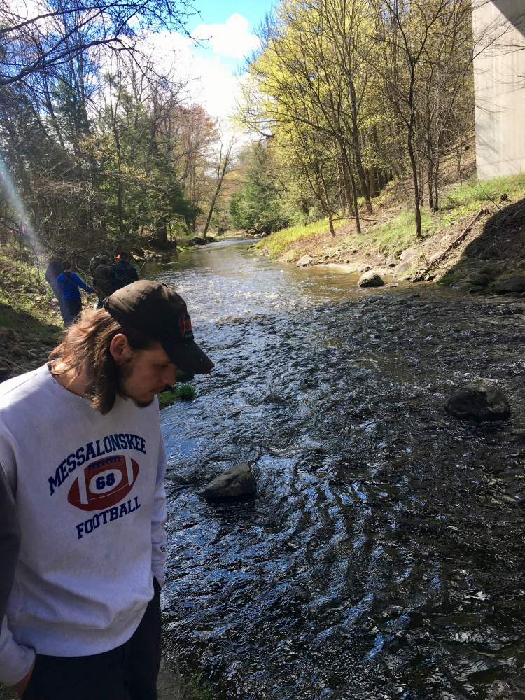 Messalonskee student Matt Trembly looks at the released Atlantic salmon in Bond Brook on May 10.