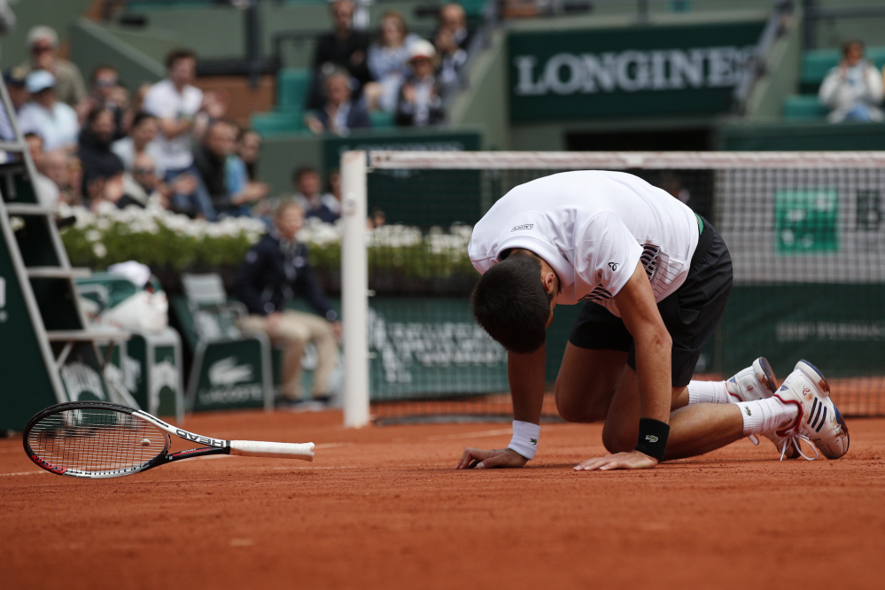 Novak Djokovic falls during his French Open quarterfinal match against Dominic Thiem on Wednesday at the Roland Garros stadium in Paris.
