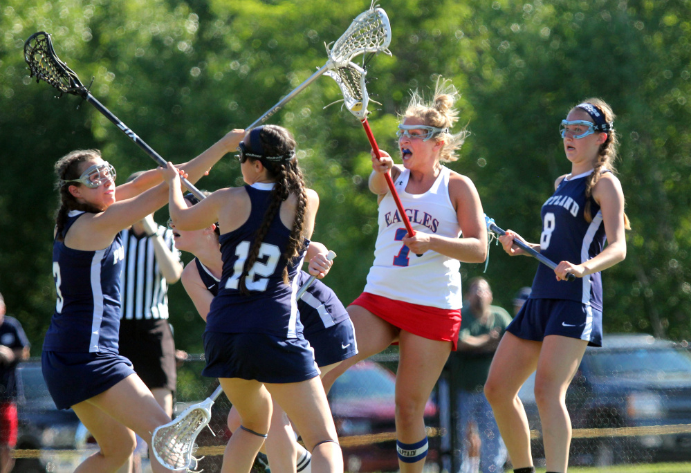 Messalonskee's Lydia Dexter fires a shot past Portland defenders Elena Clifford, left, Charlie Green (12) and Sarah Bryan (8) during the first half of a Class A North girls lacrosse quarterfinal Wednesday at Thomas College.
