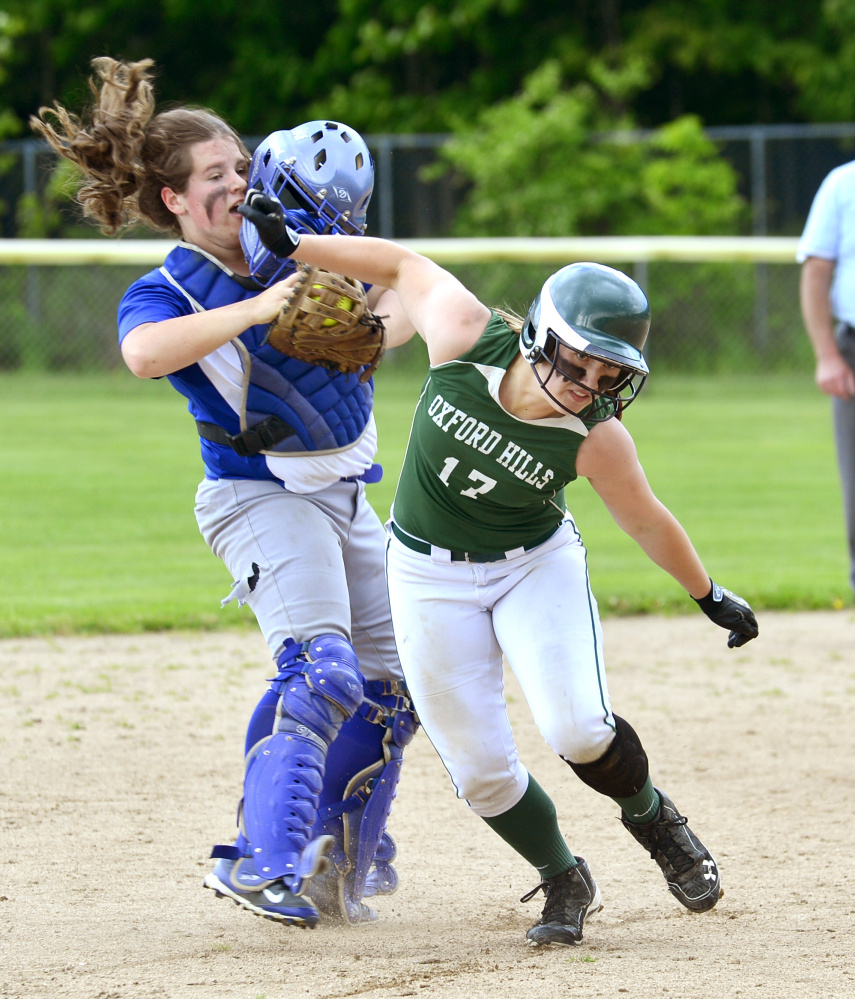 Lawrence catcher Haley Holt gets her face mask knocked off while chasing Oxford Hills Hannah runner Kenney between second and third base during a Class A North semifinal game Saturday in South Paris.