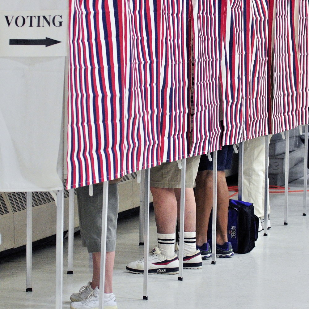 Four voters cast ballots in voting booths June 10, 2014, in the Augusta Armory. Towns around central Maine are heading to the polls Tuesday.