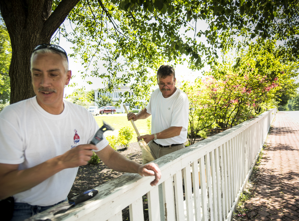 Painters Jeff Gregoire, left, of Augusta and Ted Brown, of West Gardiner, work in the shade as they scrape and paint the fence at the Blaine House in Augusta on Monday. The temperature reached to the 90s, prompting Augusta elementary schools to let students go home early.
