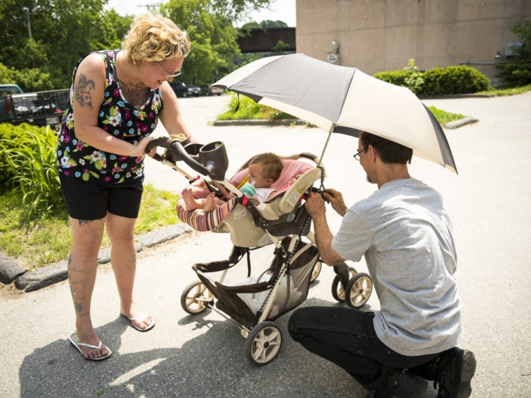 Parents Nicole and Joe Carter, of Augusta, adjust an umbrella and stroller in an effort to keep their 8 month old daughter, Persephone, shaded and cool as they walk down Water Street in Augusta on Monday.
