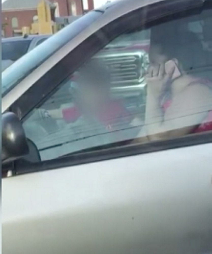 This screenshot from a video posted on Facebook by Lauren Hartsock shows a toddler unrestrained in the front seat of a minivan on Wednesday in Skowhegan as a woman drives while talking on a cell phone.