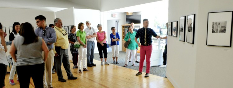 Nate Towne, of WatervilleCreates!, speaks about photos in the "Picturing Waterville" exhibit at Common Street Arts to a group of people who went on a walking tour of downtown Waterville on Wednesday to see the ongoing construction and renovation projects.