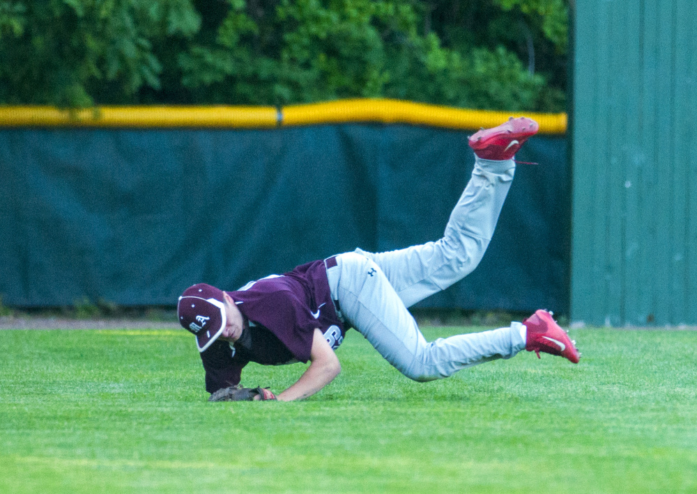 Monmouth left fielder Kane Gould somersaults in foul territory after catching a foul flyball for an out during the Class C South championship game Wednesday at St. Joseph's College in Standish.