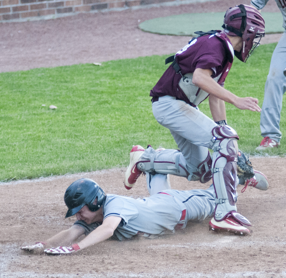 Nick Austin slides safely into home under Monmouth catcher Corey Armstrong in the Class C South championship game Wednesday at St. Joseph's College in Standish.