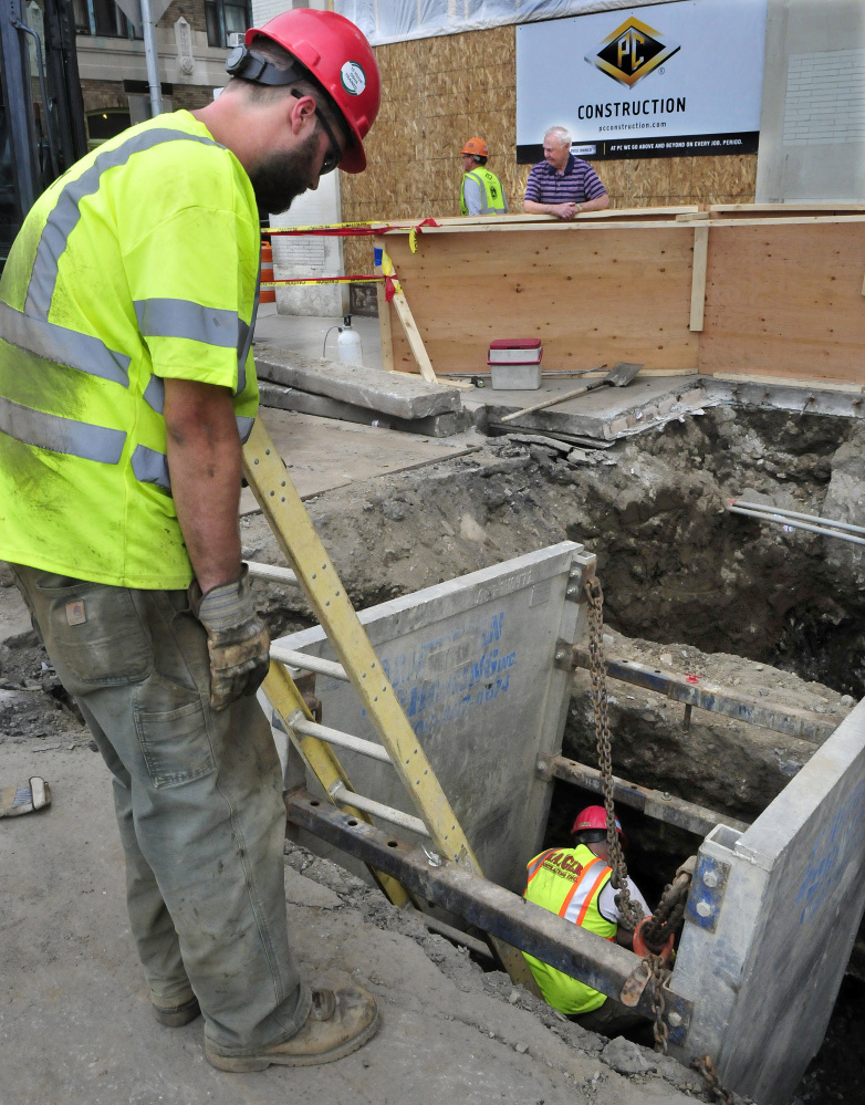 Bob Pellerin, back center, watches workers install new water lines May 24 at 173 Main St. in Waterville. On Monday, traffic on Appleton Street will be allowed one way only from the drive-thru exit of TD Bank to Front Street while work progresses on water pipes.