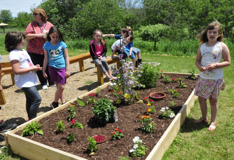 Bloomfield Elementary School student Gabby Goding explains how the class used donated materials and plants to create a garden to attract butterflies at the Skowhegan school Wednesday as teacher Lori Swenson looks on.