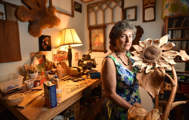 Laurie Sproul poses for a portrait with her sunflower wood sculpture in her studio at her home in Canton on Friday. Sproul is one of two Maine artists working to create a visual language for the Citizens' Climate Lobby.