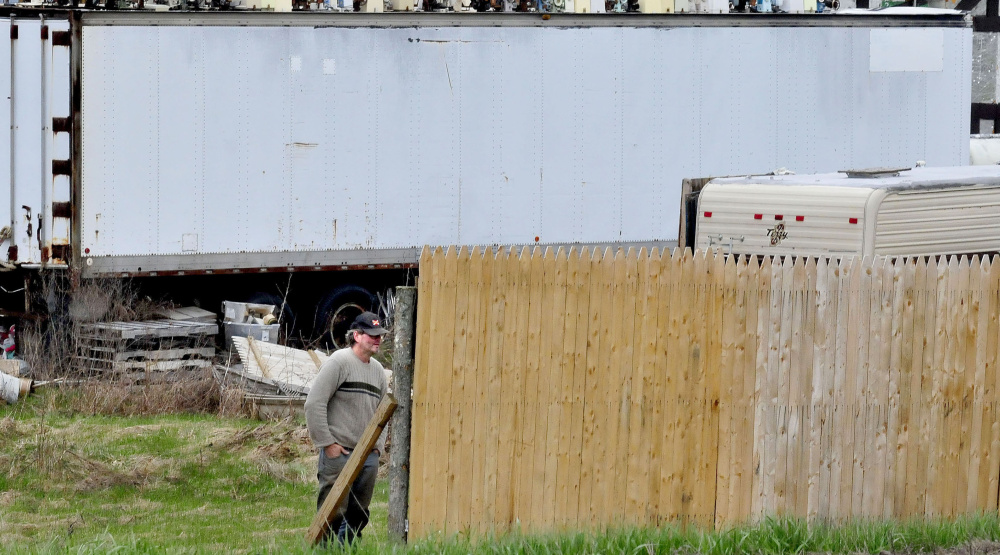 Robert Dale, owner of 201 Antiques, watches as another man, not visible in the photo, erects a fence around used merchandise in the front of the Fairfield business in May.