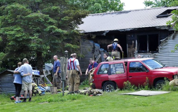 Firefighters from several area departments battled a fire that destroyed a home Thursday on Higgins road in Pittsfield. Homeowner Tyler Bishop, second from left, is comforted by a woman.