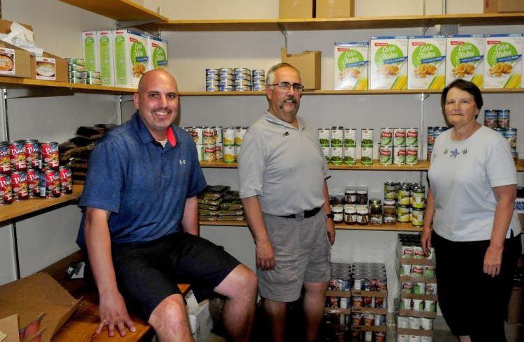 SAD 59 staff members and volunteer members of the Central Food Pantry in Madison Junior High School stand inside the stocked pantry Thursday. From left are Ryan Arnold, Al Veneziano and Doris Lindblom.