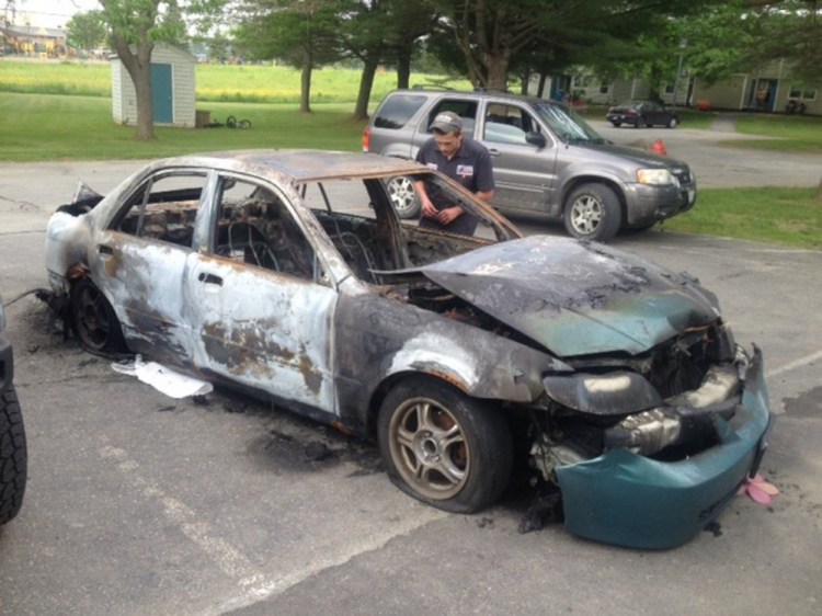 Quincy McLaughlin, of Family Circle in Skowhegan, looks over his 2001 Mazda Protege, which was consumed by fire June 12. A 15-year-old boy has been charged with arson in connection with the setting of four car fires in Skowhegan.