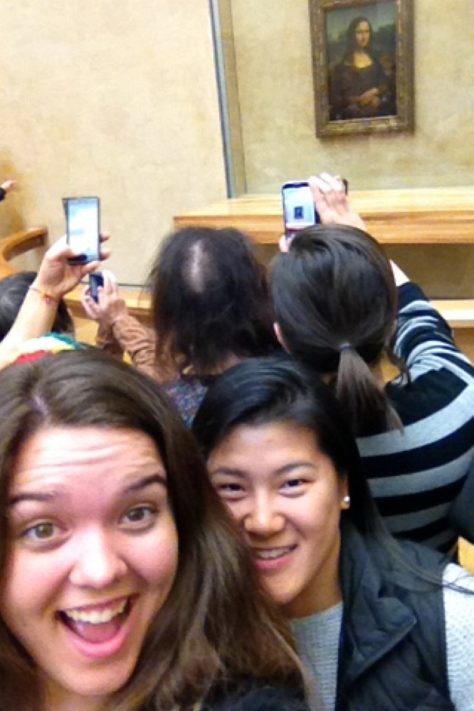 Emily Higginbotham, left, takes a selfie with friend Hannah O'Neill at the Louvre Museum in France with the "Mona Lisa" displayed in the background.