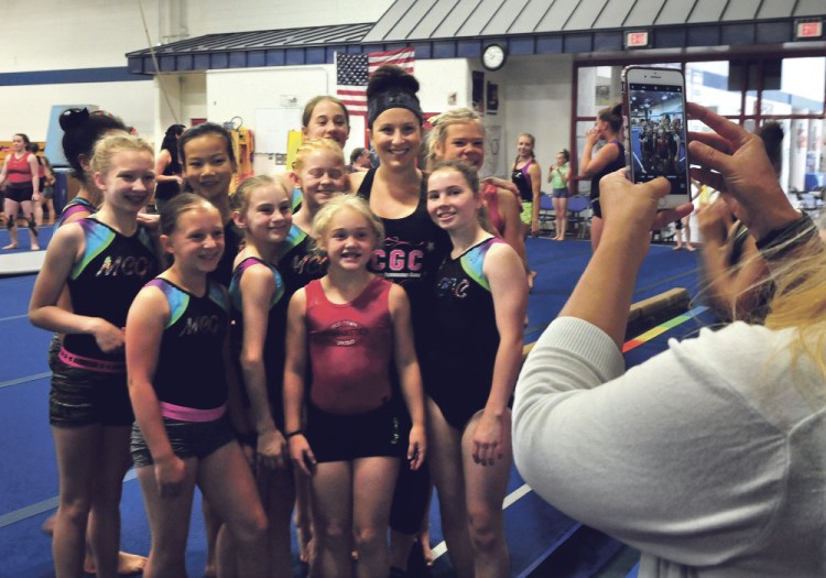 Olympic gold medalist Carly Patterson is surrounded by young area gymnasts as Kristen Starbird photographs the group during training Thursday at the Alfond Youth Center in Waterville.