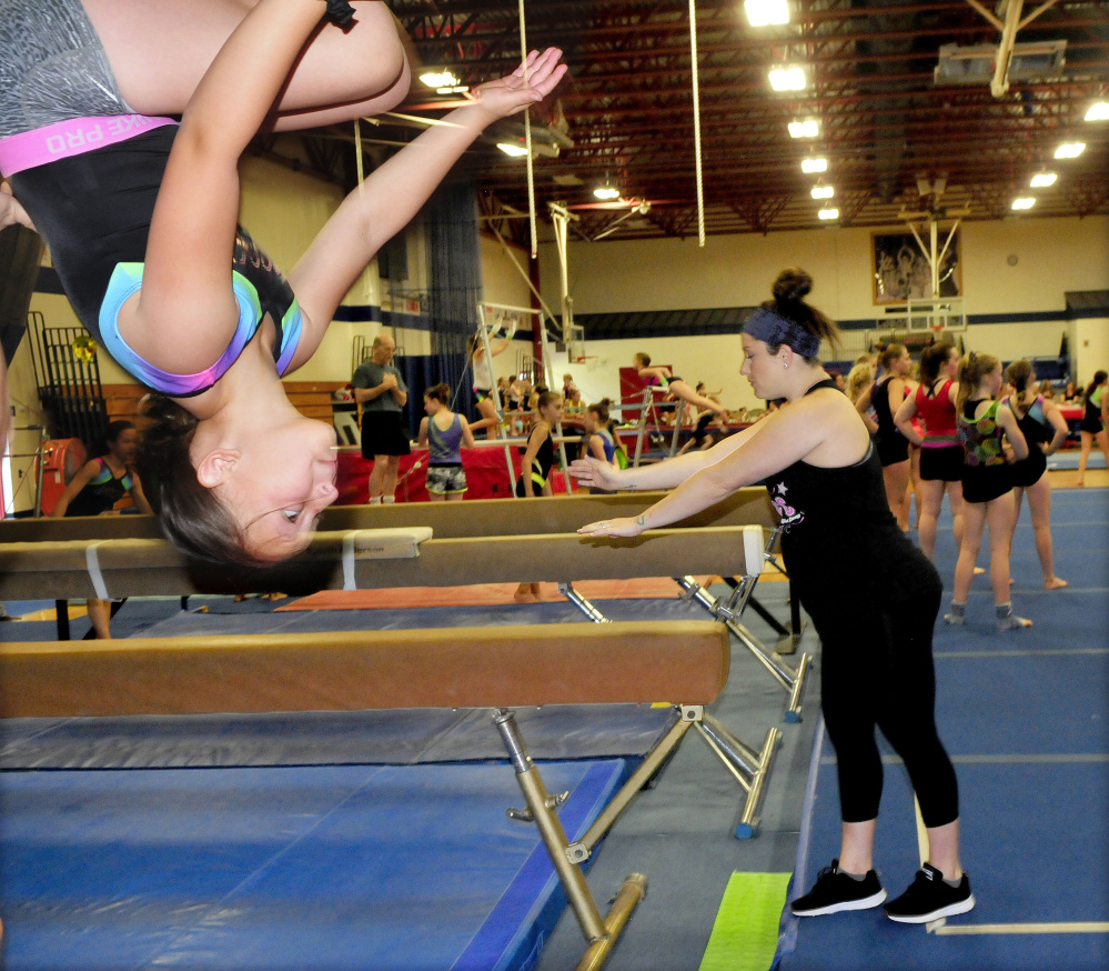 An area gymnast flips on a beam as Olympic gold medalist Carly Patterson watches other young gymnasts train Thursday at the Alfond Youth Center in Waterville.