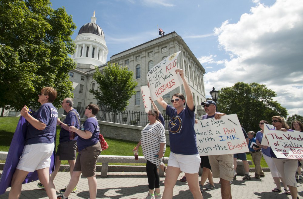 State employee union members, employees and supporters march past the State House on Monday as they protest day three of a state shutdown in Augusta.