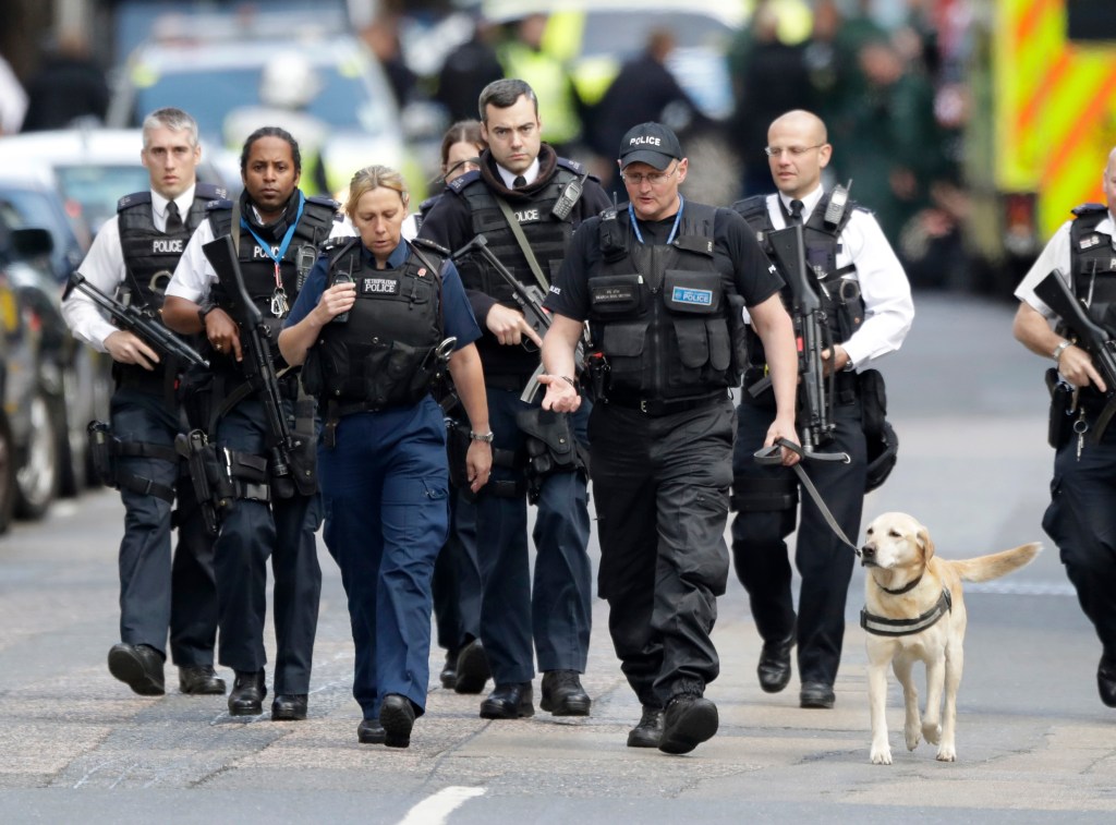 British police officers walk with a detection dog within a cordoned-off area after the attack in London on Sunday.