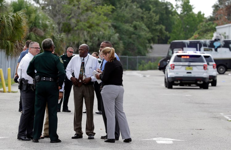 Authorities confer near the scene of a fatal shooting in an industrial area near Orlando, Fla., on Monday.