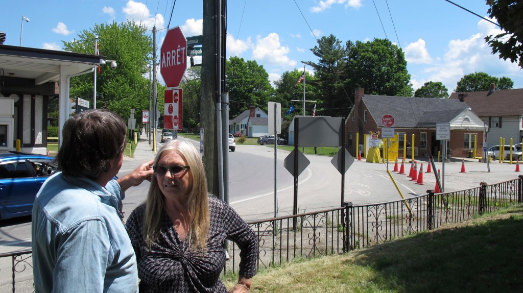 Brian and Joan DuMoulin stand in front of their apartment building that straddles the U.S.-Canadian border. To the left is a Canadian border post, and to the right, a U.S. post. 