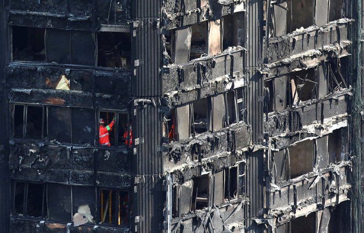 Investigators work inside  the burned-out remains of the Grenfell apartment tower in North Kensington, London, on Sunday.