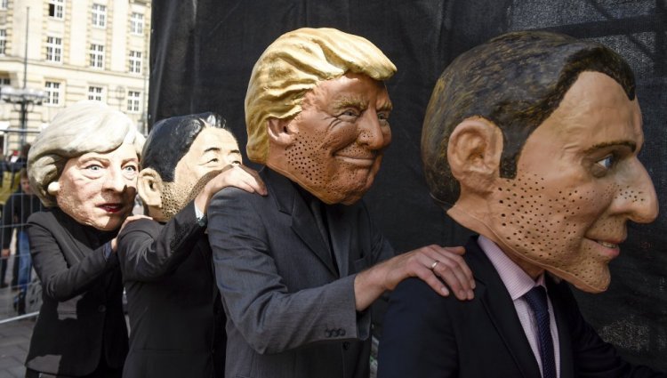 Critics of the G20 Summit stand on stage in Hamburg, Germany, wearing masks depicting, from left: British Prime Minister Theresa May, Japan Prime Minister Shinzo Abe, President Trump and French President Emmanuel Macron.