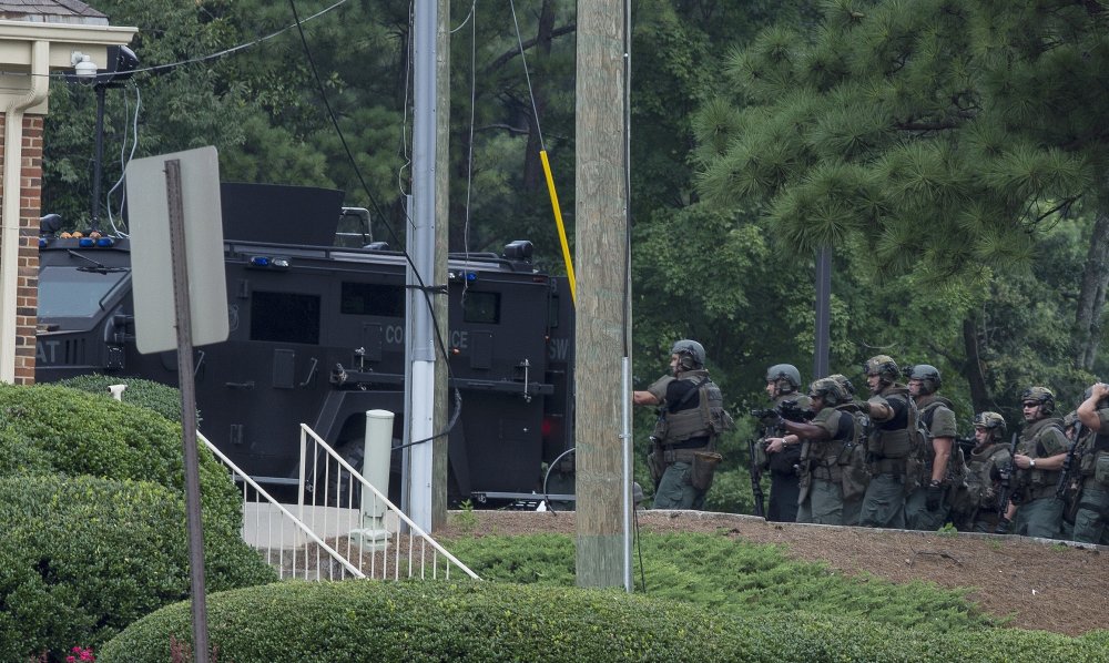 Police officers move toward a Wells Fargo Bank on Friday in Marietta, Georgia. A man who claimed to have a bomb that could "take out the room" barricaded himself inside the suburban Atlanta bank Friday, sparking an hours-long standoff that forced police to bust through a brick wall of the building and later ended with the suspect's death.