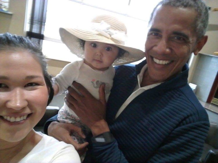 In this photo provided by Jolene Jackinsky, former President Barack Obama holds Jackinsky's 6-month-old baby girl while posing for a selfie with the pair at a waiting area at Anchorage International Airport in Alaska. Jackinsky said Obama walked up to her and asked, "Who is this pretty girl?"