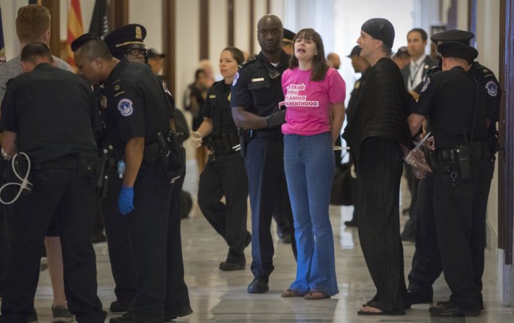 Activists protesting the Republican health care bill Monday are taken into custody by U.S. Capitol Police outside Senate offices on Capitol Hill.