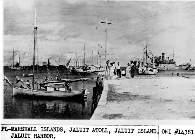 This undated photo discovered in the U.S. National Archives by Les Kinney shows people on a dock in Jaluit Atoll, Marshall Islands. A new documentary film proposes that this image shows aviator Amelia Earhart, seated third from right, gazing at what may be her crippled aircraft loaded on a barge.
