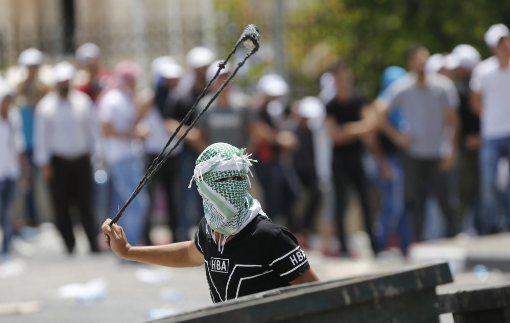 A Palestinian uses a slingshot against Israeli soldiers during clashes Bethlehem on Friday. At issue are metal detectors Israel installed at a Jerusalem shrine earlier this week.