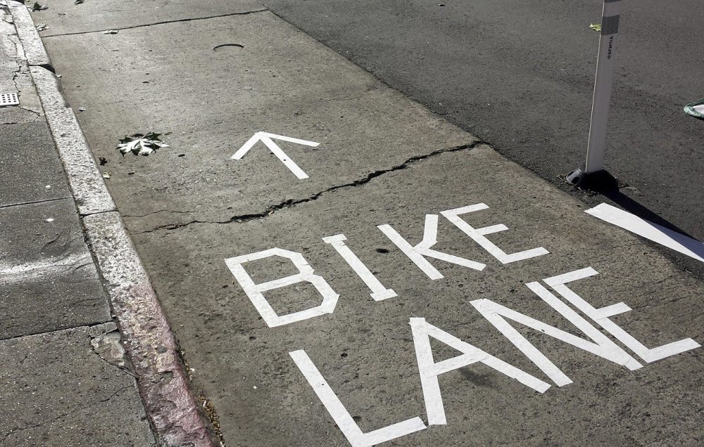 A sign made by activists with tape separates cyclists from traffic on a San Francisco street.