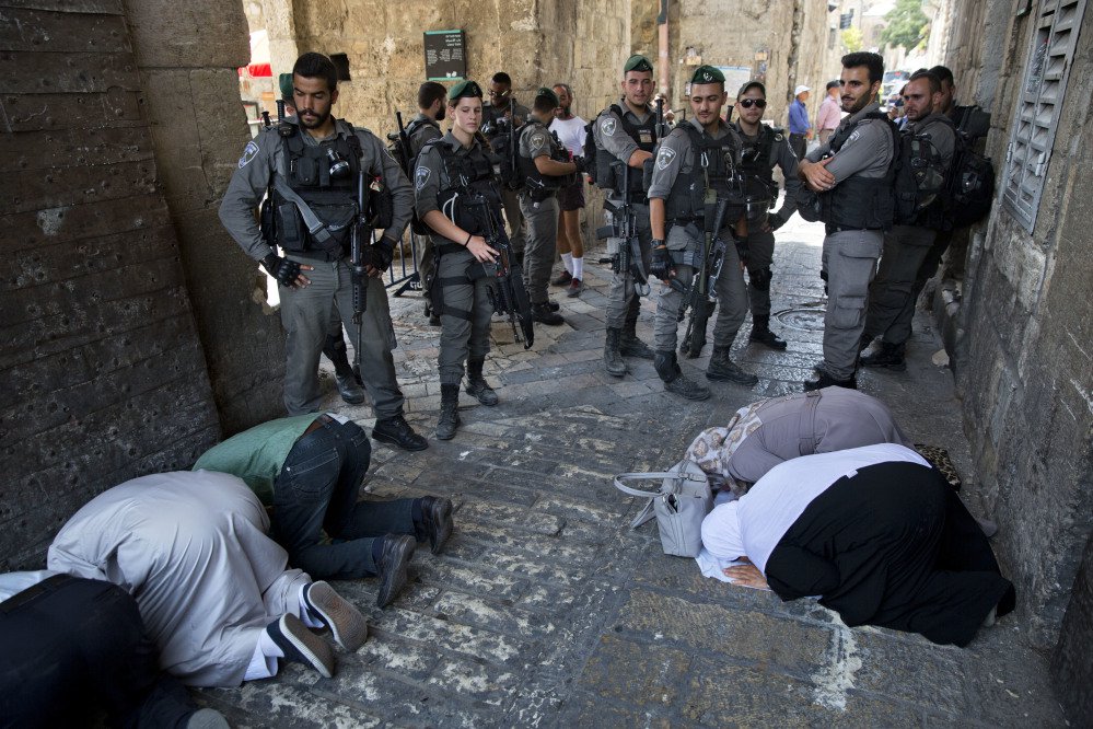 Palestinian Muslims pray in protest as Israeli police stand guard in Jerusalem on Tuesday. The protestors contested Israel's installation of a metal detector at a holy site.