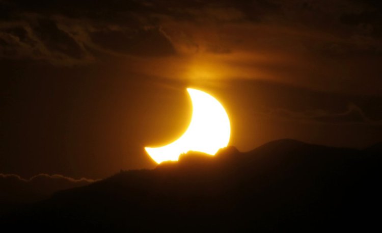 The annular solar eclipse is seen as the sun sets behind the Rockies from downtown Denver on May 20, 2012.