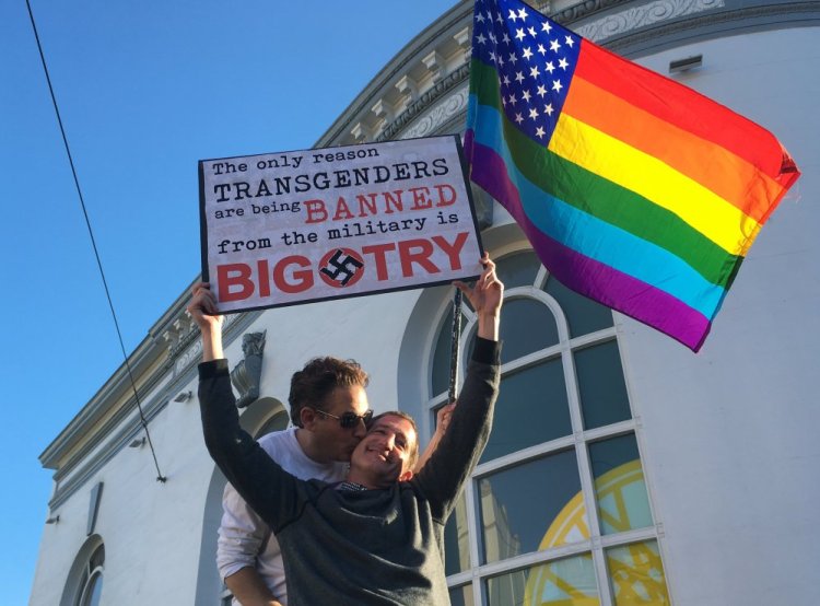 Nick Rondoletto, left, and Doug Thorogood, a couple from San Francisco, wave a rainbow flag and hold a sign against a proposed ban of transgendered people in the military at a protest in the Castro District in San Francisco. Demonstrators flocked to a plaza named for San Francisco gay-rights icon Harvey Milk to protest President Trump's abrupt ban on transgender troops in the military.