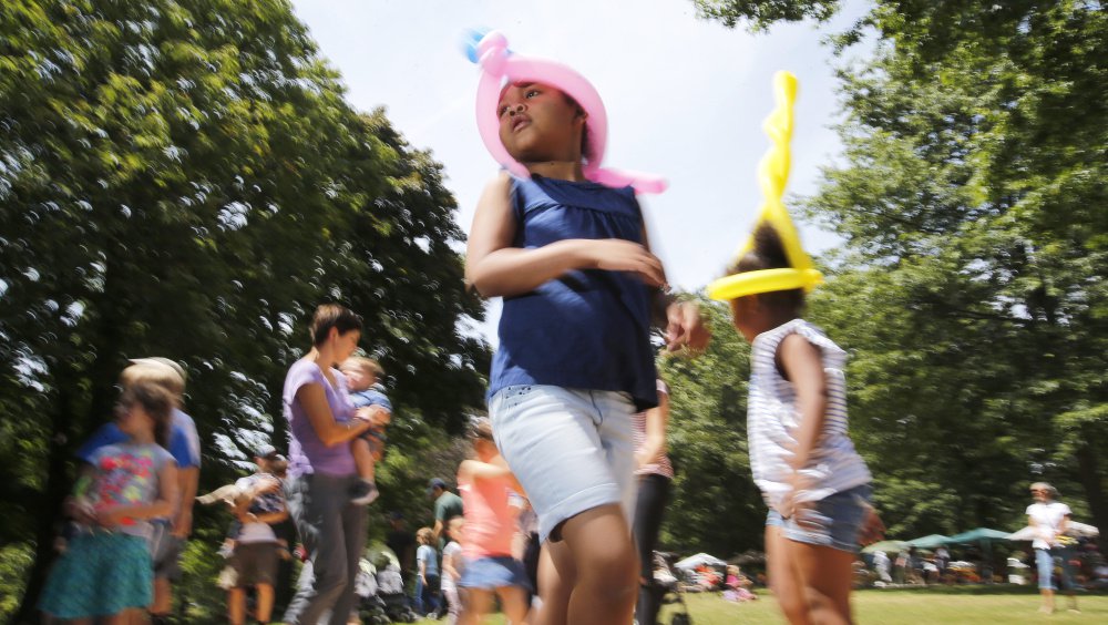 Sisters Aisa, center, and Doris Gongbu sport balloon hats while taking a salsa dance lesson Saturday in Deering Oaks as part of the Festival of Nations. People attended the fair for the food, the fun, and the celebration of Maine's ethnic diversity.