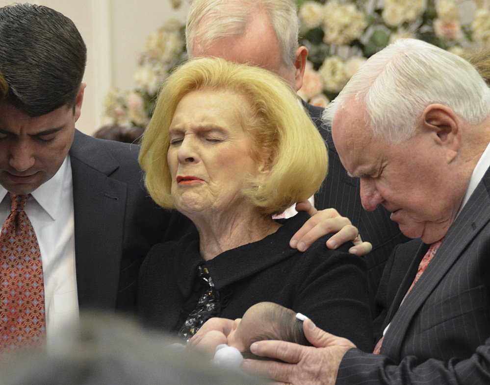 Word of Faith Fellowship leader Jane Whaley holds a member's infant daughter, accompanied by her husband, Sam, right, and others at the church in Spindale, N.C.