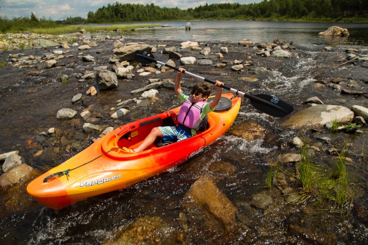 Tyler Flory, 10 of Amherst, Mass., rides a kayak through a mini rapid at the out flow of Third Roach Pond.