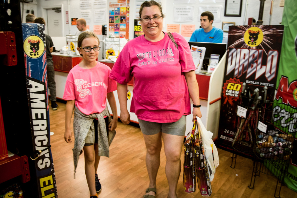 Gwendolyn LaCombe, 10, and her mother Jennifer, of Lewiston, purchase variety packs of fireworks and "snappers" at Pyro City Fireworks in Manchester on Saturday.