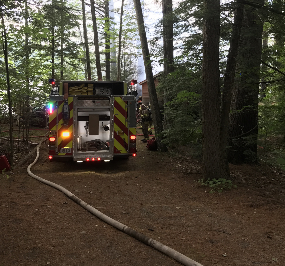 Firefighters work to extinguish a camp fire early Tuesday evening on Maranacook Lake in Readfield.