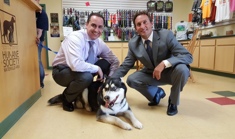 Darrick Banda, left, and David Bobrow, both attorneys for Matthew Perry, pose with Dakota the husky at the Humane Society Waterville Area.