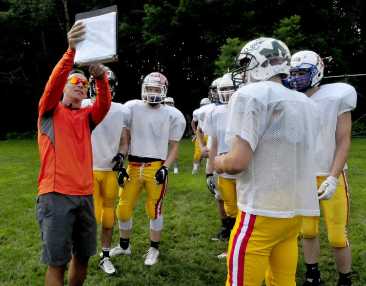 East offensive coordinator Matt Friedman goes over plays with players during Lobster Bowl practice Tuesday at Dover-Foxcroft.