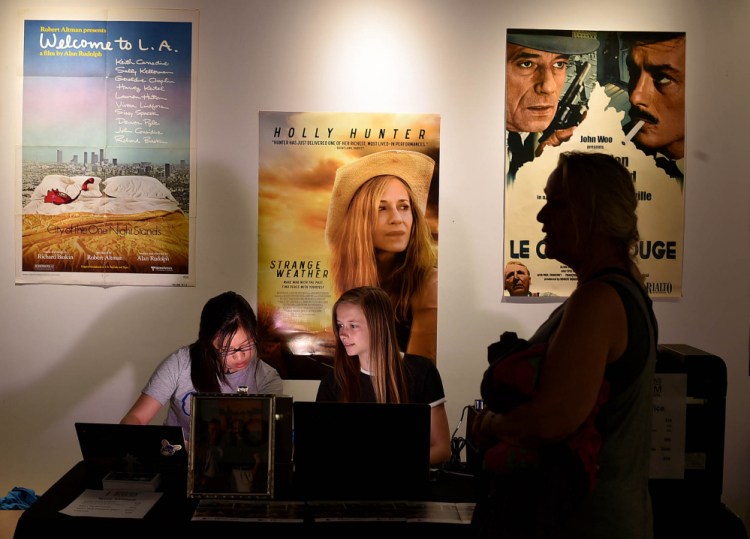 Sunny Dangui, left, and Amanda Schmidt, center, sell a MIFF pass Wednesday to Edda Thiele, right, at Railroad Square Cinemas in Waterville.
