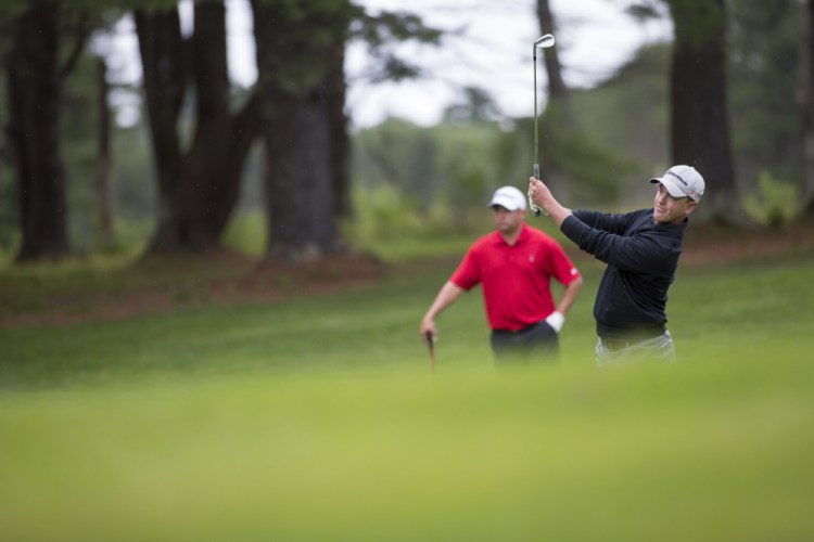Sam Grindle, left, looks on as Jack Wyman hits a shot during the final round of the Maine Amateur golf tournament Thursday at the Brunswick Country Club.