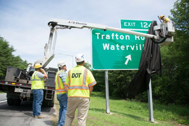Workers with the Maine Department of Transportation unveil the sign on Friday for the new exit 124 off Interstate 95 in Waterville connecting with Trafton Road.