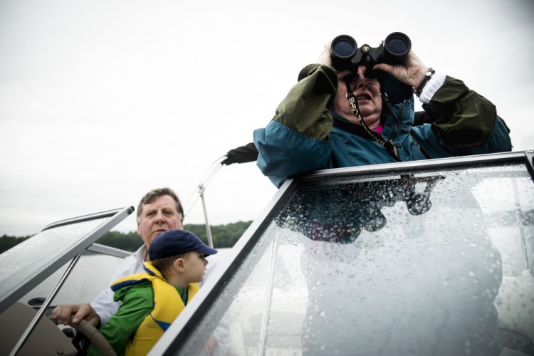 Grandparents Norval "Tad" Garnett, left, and his wife, Karen, summer residents of China, take their grandson Calder Amoroso, 2, of Providence, R.I., out on their boat Saturday on China Lake in search of loons during the annual Maine Audubon loon count.