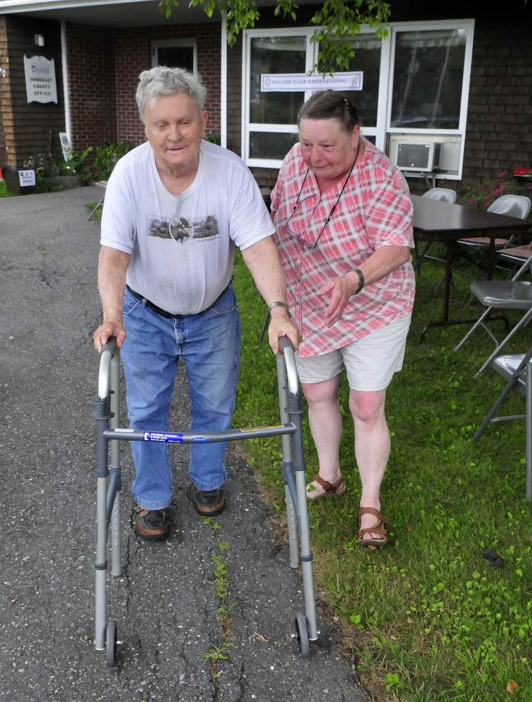 Charlie McLeod is helped by Debra LeCourt at the Senior Gathering in Skowhegan on Wednesday.