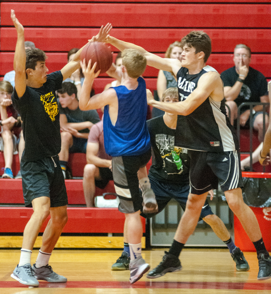 Maranacook's Jackson McPhedran, left, and Silas Mohlar, right, double-team Lawrence's Jackson Dudley during a summer league game Wednesday at Cony High School in Augusta.